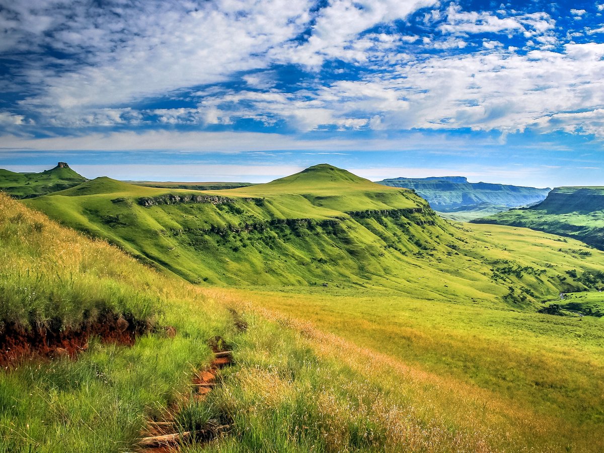 Panoramablick auf Berglandschaft in verschiedenen Grüntönen mit dramatischen Wolkenhimmel.