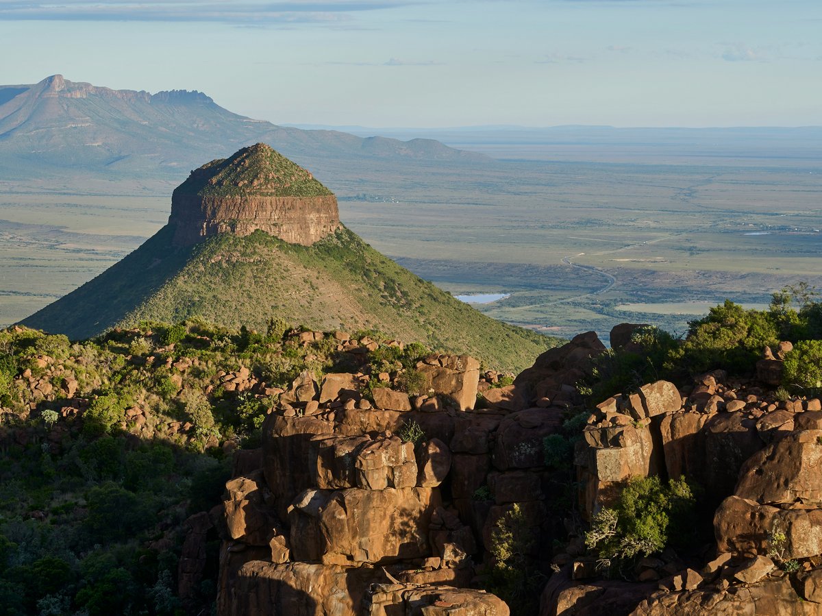 Felsige Landschaft mit markantem Tafelberg und weitem Tal unter blauem Himmel mit Wolken.