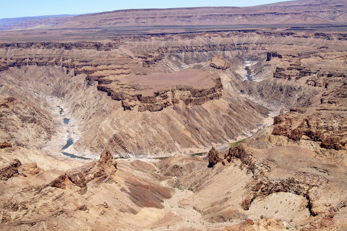 Luftaufnahme einer sehr trockenen Gebirgslandschaft durch die sich ein Fluß schlängelt