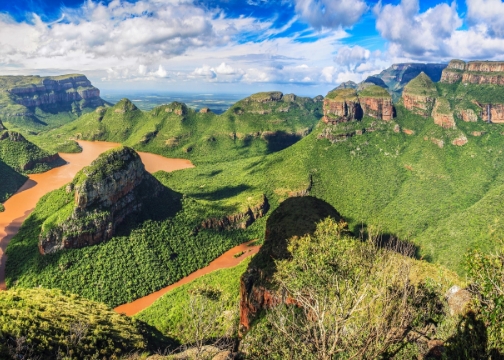 Blick über eine tiefe, grün bewachsene Schlucht, im Hintergrund drei markante, rundliche Felsformationen